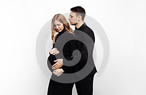 Man stands behind his pregnant wife and smiles, hugging her on a white isolated background