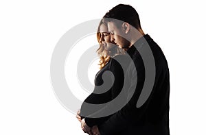 Man stands behind his pregnant wife and smiles, hugging her on a white isolated background