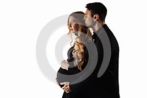 Man stands behind his pregnant wife and smiles, hugging her on a white isolated background