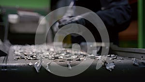 Man stands at conveyor removing non-recyclable items out of silver particles stream slow motion