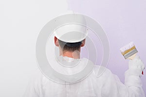 A man stands in front of the wall with a brush for painting the wall