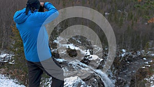 A man stands on a high point in the mountains and admires a beautiful view. There are peaks around it and a beautiful