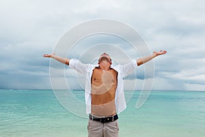 Man stands with his hands raised up on the beach