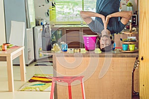 A man stands on his hands upside down in the kitchen