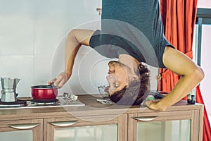 A man stands on his hands upside down in the kitchen