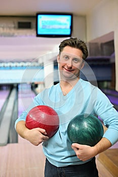 Man stands and holds two balls for bowling