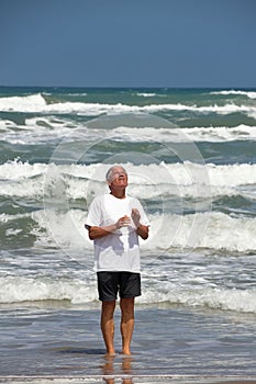 Man stands in ocean, praying