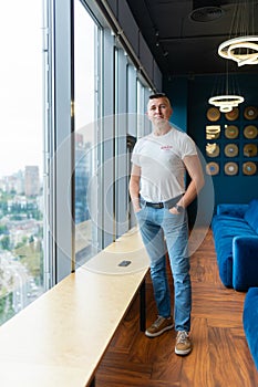 Man stands in office lounge zone in casual clothing