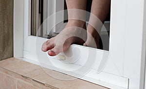 A man stands in an open window. The man wants to jump out of the window. Feet are on the window. Suicide