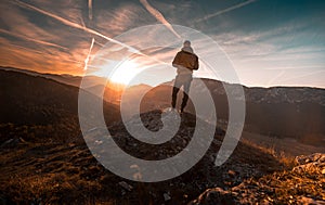 Man stands on the peak of a mountain and watching to Sun. Beautiful moment the miracle of nature