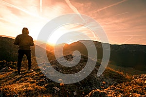 Man stands on the peak of a mountain and watching to Sun. Beautiful moment the miracle of nature