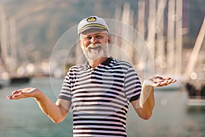 Man stands on pier dressed in a sailor`s shirt and hat