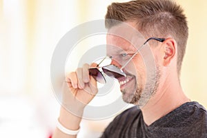 Man stands in profile and measures his sunglasses.