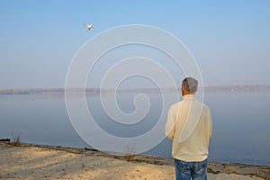 A man stands on the river bank and controls the drone.