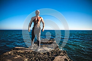 Man stands on a rock by the sea against the sky