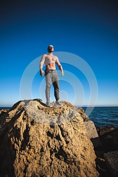 Man stands on a rock by the sea against the sky