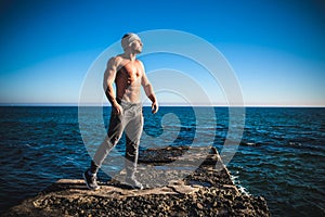 Man stands on a rock by the sea against the sky