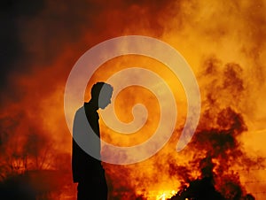 a man stands silhouetted in front of a bush fire