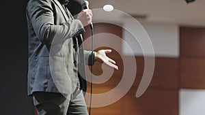 A man stands on a stage with a microphone in his hand