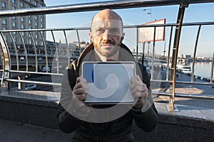 A man stands on the street with a blank sign from the license plate