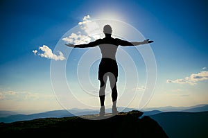 Man stands on top of a mountain with open hand