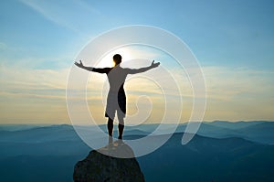 Man stands on top of a mountain with open hands