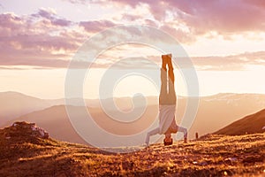 Man stands upside down at mountain sunset