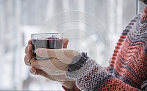 A man stands at the window with a cup of mulled wine in his hand