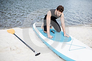 Man with standup paddleboard on the beach
