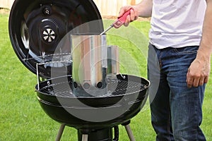 Man starting BBQ coal chimney fire with lighter