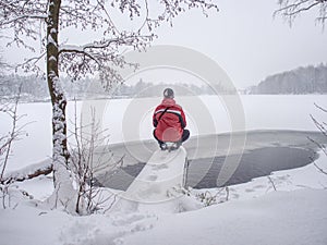 Man stay at end of pipe above water of unfrozen lake. Winter day