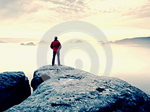 Man is staying on a top of a rock above clouds. Man on mountain.