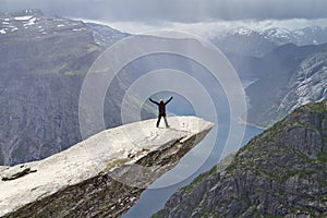 Man staying on Trolltunga rock and looking at Norwegian mountain landscape