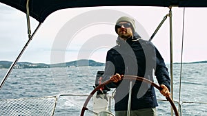 Man steering a sailboat. Windy day