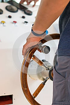 Man steers a sea river vessel boat. Strong male captain`s hand on the helm handle of a yacht ship