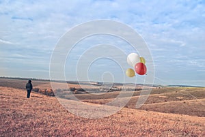 Man in the steppe in the fall. Balloons fly in the field. Post processing photo