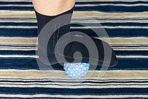 a man stepping on a peanut-shaped massage ball to relax his muscles at horizontal composition