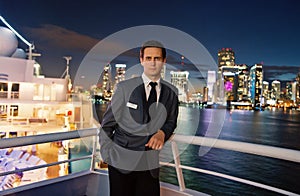 Man steward on ship board at night in miami, usa. Macho in suit jacket on city skyline. Water transport, transportation