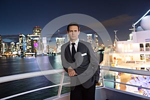 Man steward on ship board at night in miami, usa. Macho in suit jacket on city skyline. Water transport, transportation. Travellin