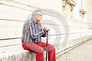 Man with stick sitting outdoor