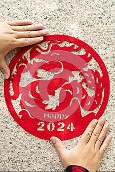 man sticking a Chinese New Year of the Dragon 2024 decoration to a wall at vertical