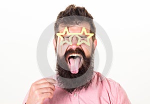 Man with stickout tongue, closed eyes and beard wearing paper star shaped glasses, fun concept. Hipster with crazy look