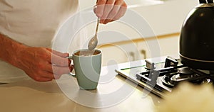 Man stirring coffee in kitchen at home 4k