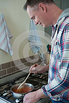 Man stirring food in pan at kitchen