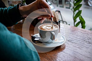 Man stirring sugar in a cup of coffee.