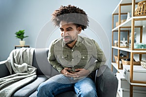 Man With Stomach Ache Sitting On Couch At Home