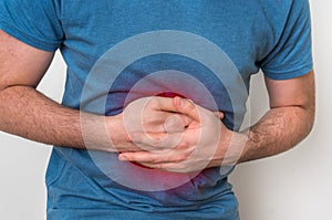 Man with stomach pain is holding his aching belly