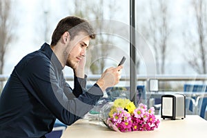 Man stood up in a date checking phone messages photo
