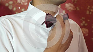 The man straightens his tie. Well-dressed young man adjusts classic red bowtie. Close-up. man straightens bow-tie close
