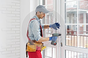 A man straightens a plastic window or door with a screwdriver.